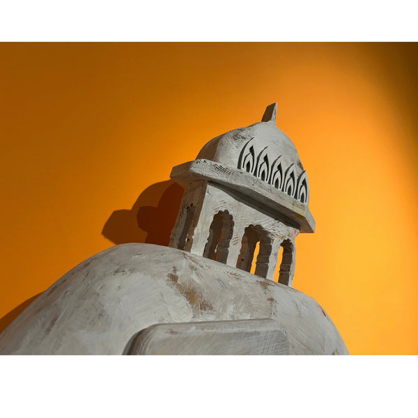 Detail of carved wooden dome architecture on Mário Belém "Don’t tell me stories" sculpture against yellow backdrop